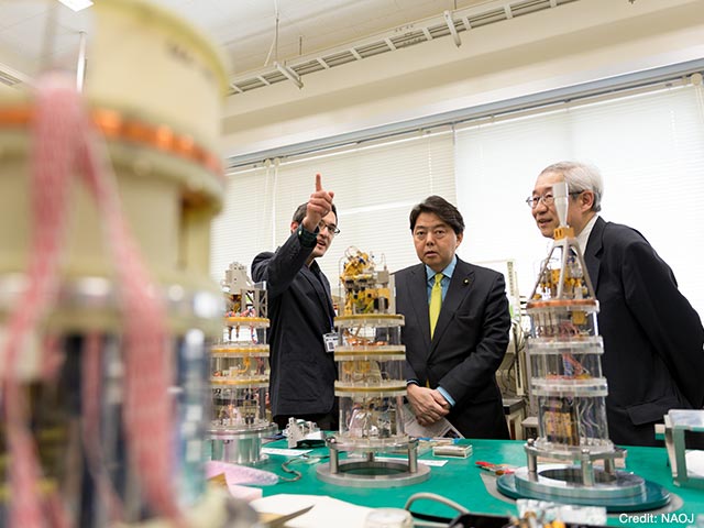 アルバロ・ゴンザレス准教授（左）と常田国立天文台長（右）からアルマ受信機の開発について説明を受けている林文部科学大臣（中央）