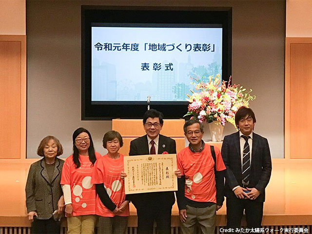 写真：賞状を手にする縣秀彦さんと実行委員会メンバー