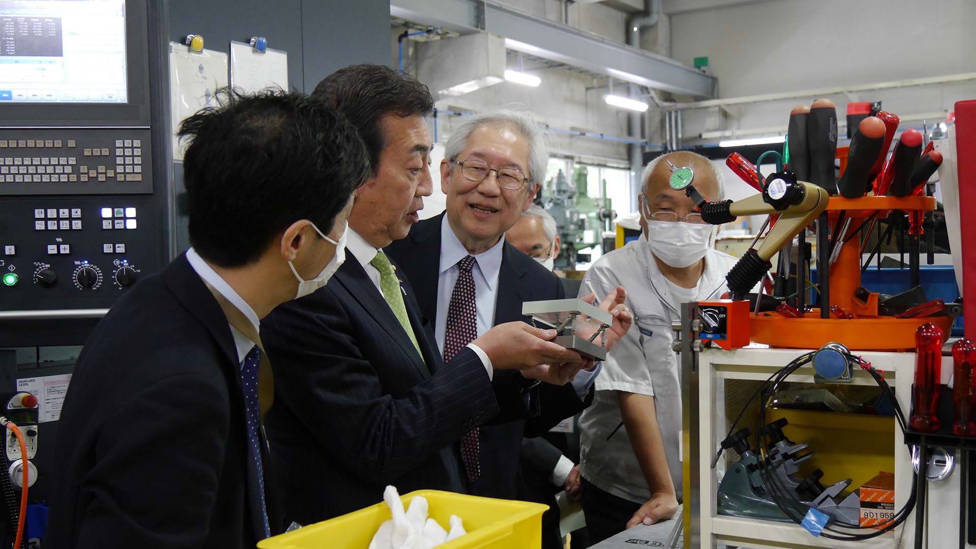 先端技術センターにて、観測機器の製作技術について説明を受ける星野内閣府副大臣（左から2人目）。