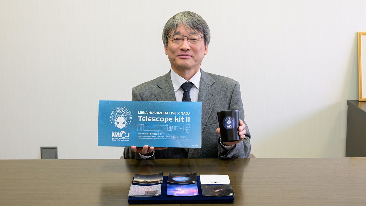 「MISIA×国立天文台」コラボレーショングッズを手に取る土居守国立天文台長。