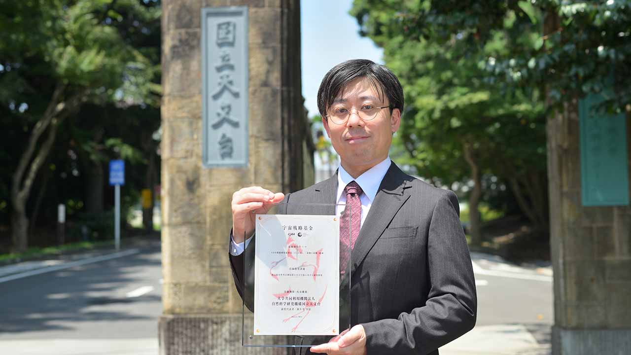 採択認定証を手にする阿久津助教