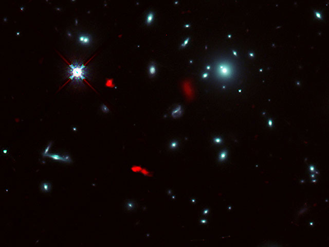 Image of the galaxy cluster RXCJ0600-2007 taken by the NASA/ESA Hubble Space Telescope, combined with gravitational lensing images of the distant galaxy RXCJ0600-z6, 12.4 billion light-years away, observed by ALMA